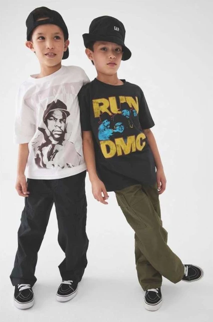 Two young boys pose in graphic T-shirts and trousers in a full shot against a white background, showcasing children's fashion.
