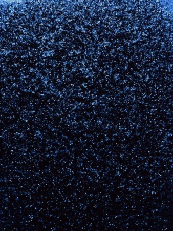 Close-up texture of a coarse, dark blue surface with scattered light-blue sparkles, creating a deep and shimmering effect.
