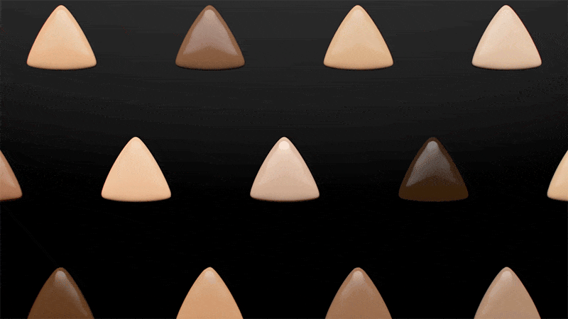 Animated display of triangular foundation sponges in varying skin tones on a black background for beauty or cosmetics advertising.