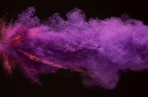 An abstract explosion of vibrant pink and purple powder against a stark black backdrop, creating a dynamic visual effect.