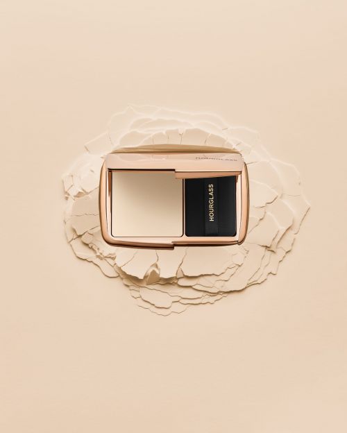 Hourglass Ambient Lighting Palette on powder pile. Close-up shot of luxury makeup compact on a neutral beige background. Beauty product.