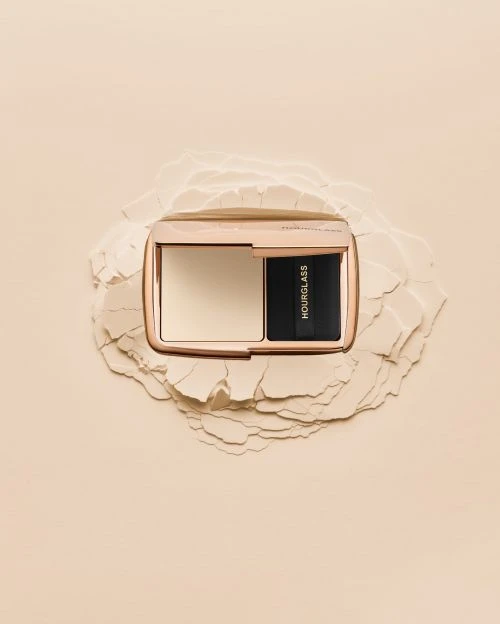 Hourglass Ambient Lighting Palette on powder pile. Close-up shot of luxury makeup compact on a neutral beige background. Beauty product.