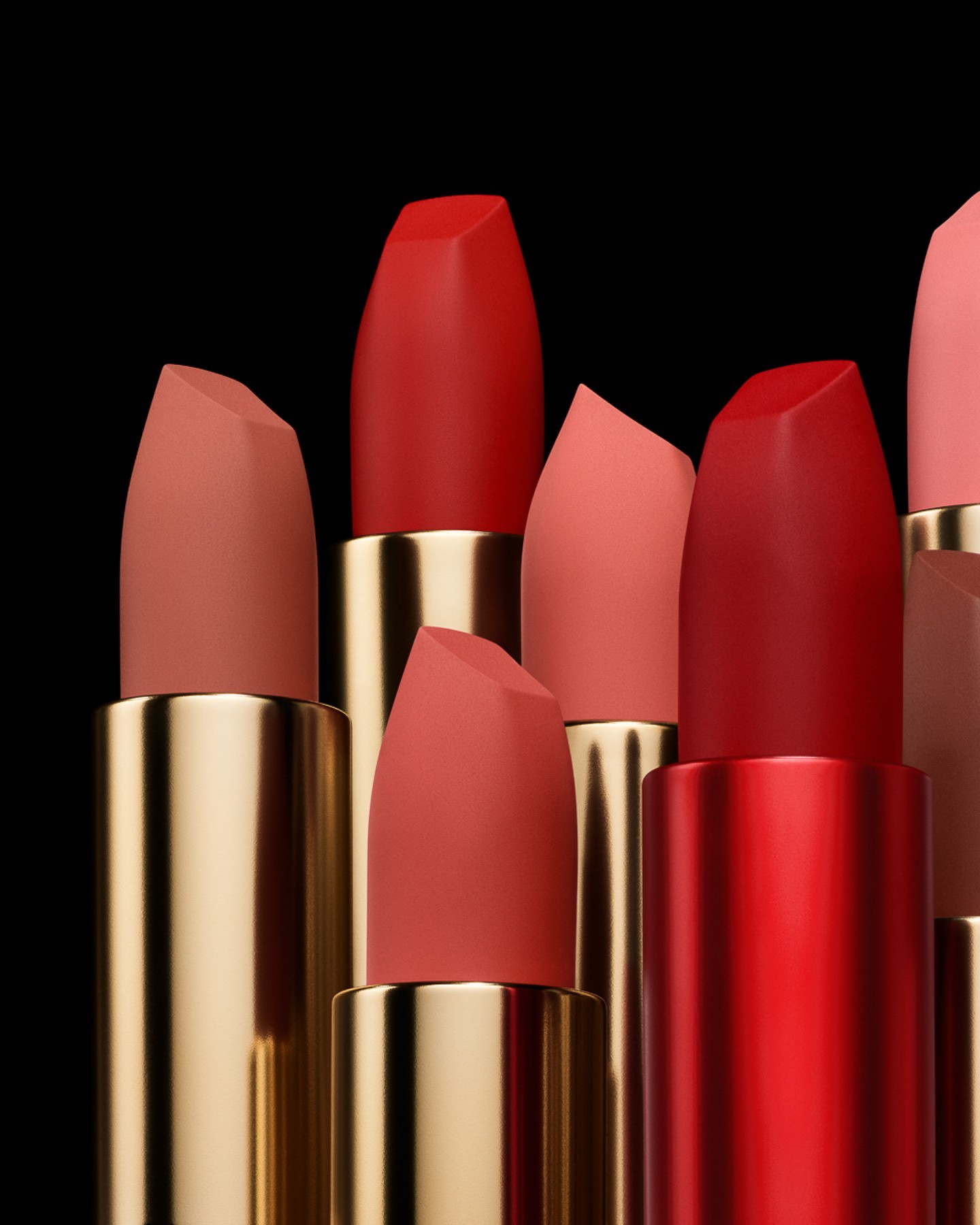 Close-up of multiple lipstick tubes in various shades of red, pink, and peach, arranged against a stark black background.