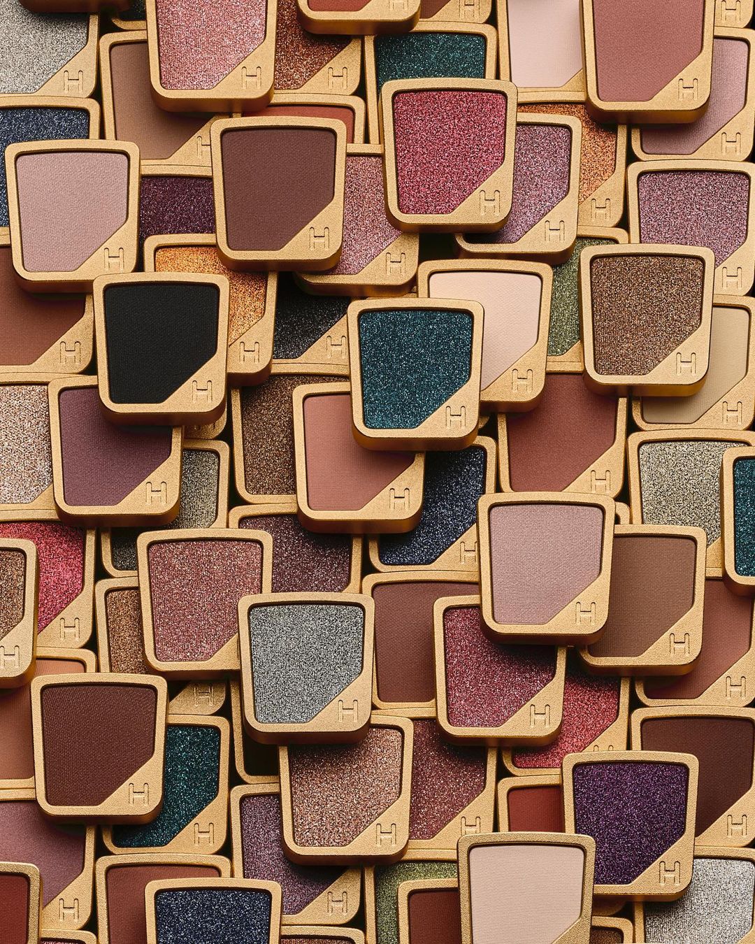 Overhead shot of an arrangement of eyeshadow palettes with various colors and the Hourglass Cosmetics logo, showcasing beauty products.