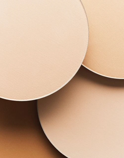 Close-up of circular cosmetic powder compacts in various neutral tones, displaying a range of shades for makeup application.