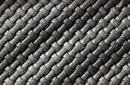 Close-up of a black woven fabric with a diagonal pattern, showcasing the texture and detail of the interlocked strands in soft lighting.