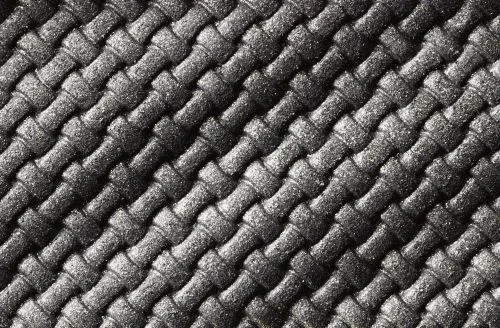 Close-up of a black woven fabric with a diagonal pattern, showcasing the texture and detail of the interlocked strands in soft lighting.