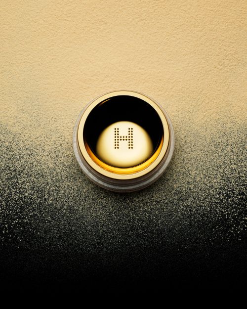 Hourglass Veil Translucent Setting Powder in a gold container, sitting on a yellow to black gradient background, beauty, makeup.