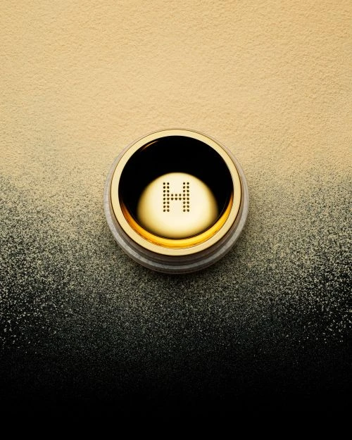 Hourglass Veil Translucent Setting Powder in a gold container, sitting on a yellow to black gradient background, beauty, makeup.