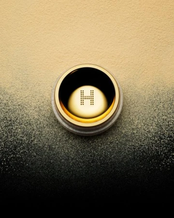 Hourglass Veil Translucent Setting Powder in a gold container, sitting on a yellow to black gradient background, beauty, makeup.