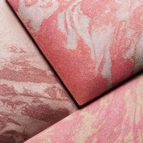 Close-up of three textured cosmetic powder compacts in shades of pink and rose, displaying a marbled, swirled pattern on each.