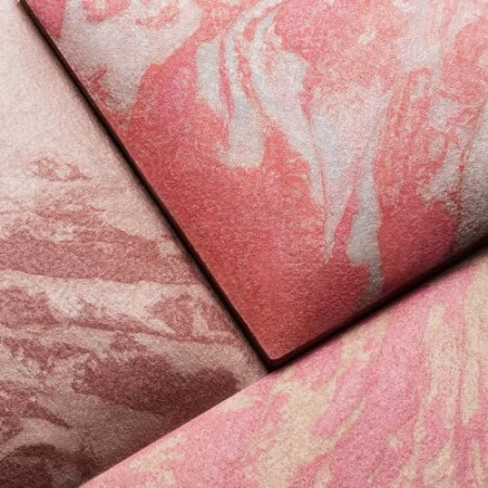 Close-up of three textured cosmetic powder compacts in shades of pink and rose, displaying a marbled, swirled pattern on each.