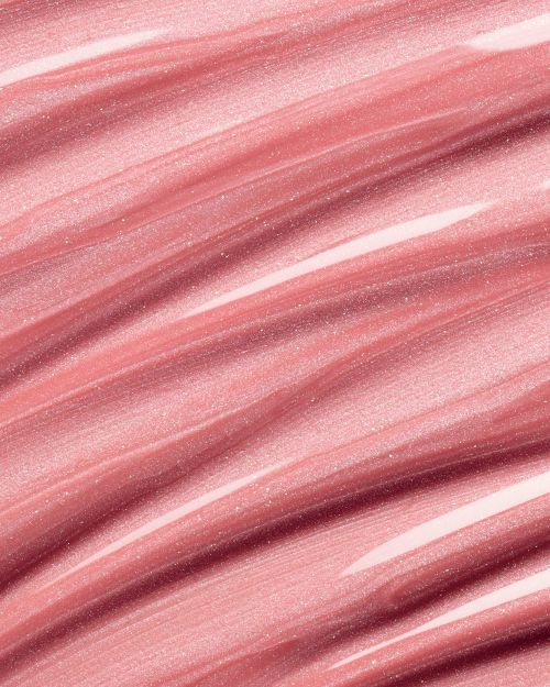 Macro image of shimmering, light pink lip gloss streaks, highlighting texture and reflective qualities, ideal for beauty or cosmetic themes.