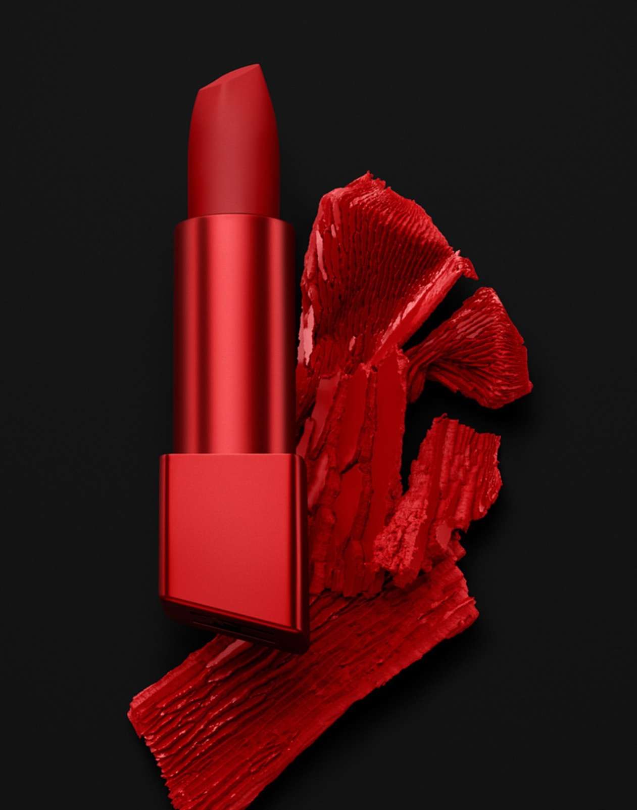 Close-up of red lipstick on a dark background, with a swipe of matching lipstick adding texture and color contrast.