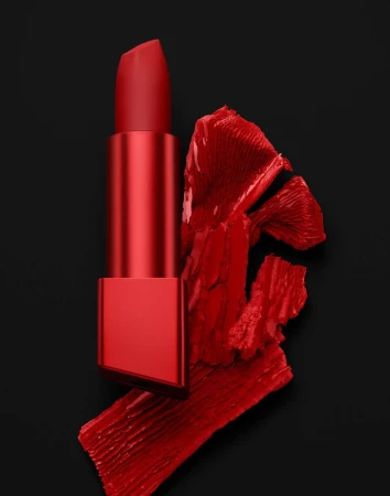 Close-up of red lipstick on a dark background, with a swipe of matching lipstick adding texture and color contrast.