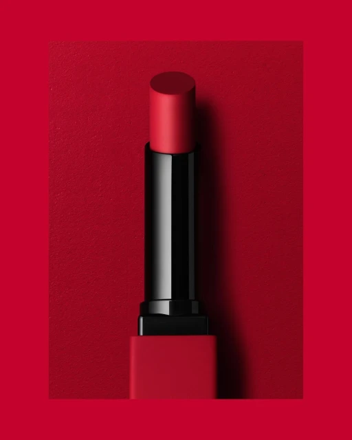 Red lipstick tube on a matching red background, clean beauty shot, minimal composition, cosmetic product photography.