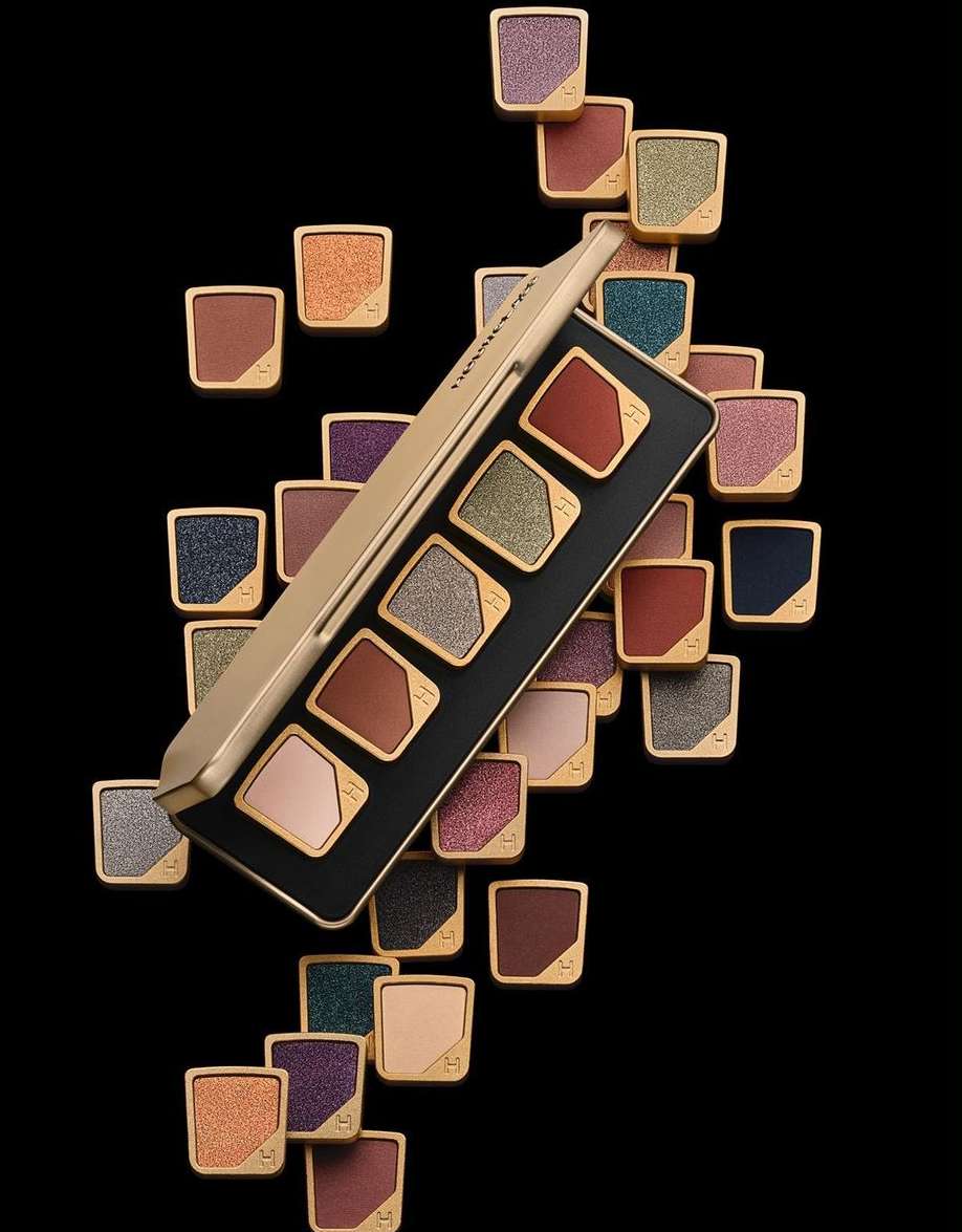 Eye shadow palette with multiple colors. Variety of glittery and matte colors in gold compact and black background, beauty product.