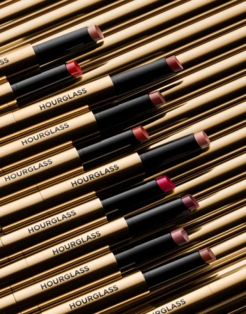 Hourglass lipsticks lined up on a gold surface in a beauty product photography arrangement, displaying a variety of shades and luxury branding.