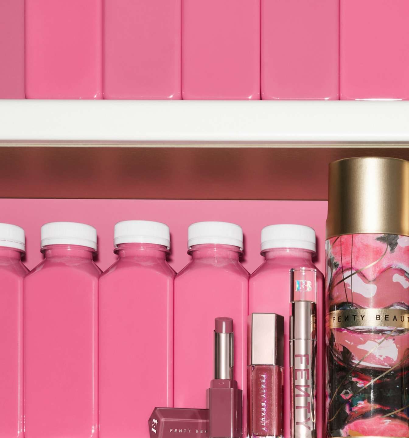 A selection of Fenty Beauty products in a monochromatic pink colour scheme, arranged on shelves with pink walls, bottles and containers.