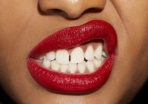 Close-up of lips wearing vibrant red lipstick with teeth biting the lower lip, captured by photographer Tory Rust.