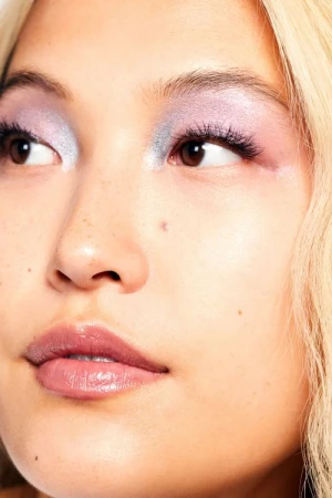 Close-up portrait of a woman with frosted lavender eyeshadow and glossy pink lips photographed by Tory Rust.