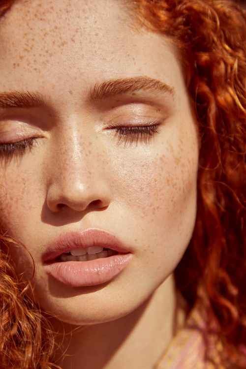 Close-up portrait of a red-haired woman with closed eyes and prominent freckles photographed by Tory Rust.