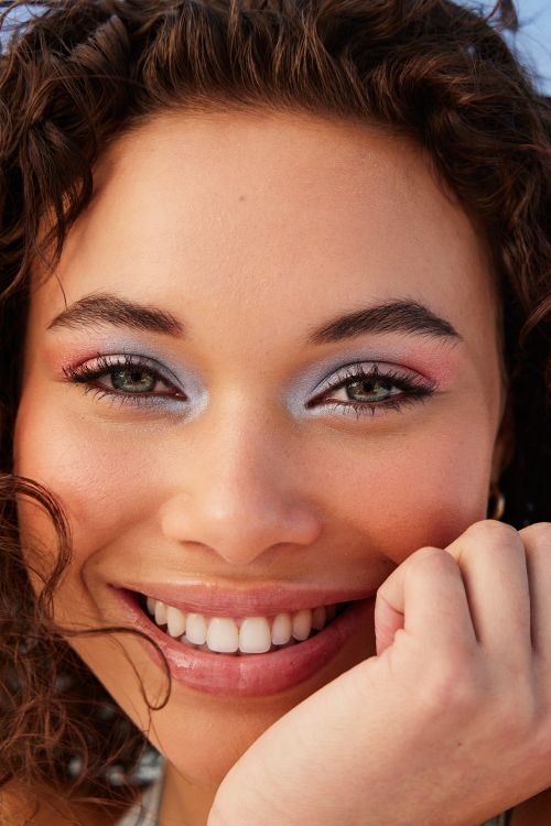 Close-up portrait of smiling young woman with curly hair wearing colorful pastel eyeshadow makeup by photographer Tory Rust