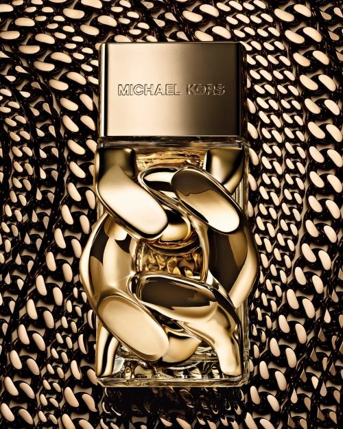 Michael Kors perfume bottle with a gold chain design set against a gold and black chain patterned background.