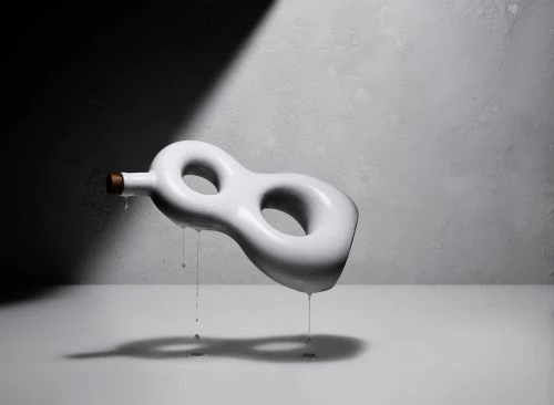 Still life shot of a white, abstract vase with liquid dripping, set against a textured gray wall with strong shadow play.