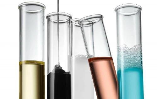 Five test tubes filled with liquids of varying colors, set against a bright white background in a laboratory setting.
