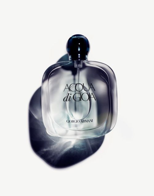 A bottle of Acqua di Gioia Giorgio Armani perfume sits on a white surface, with an overhead shot capturing its translucent design.