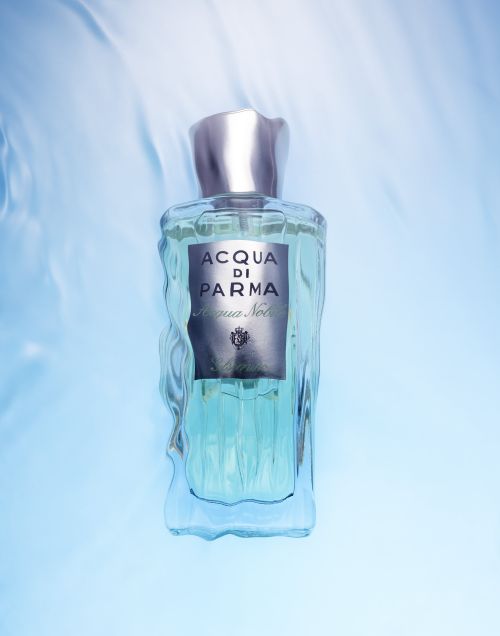 A bottle of Acqua di Parma Colonia Nobile perfume against a light blue background with a subtle water texture effect.