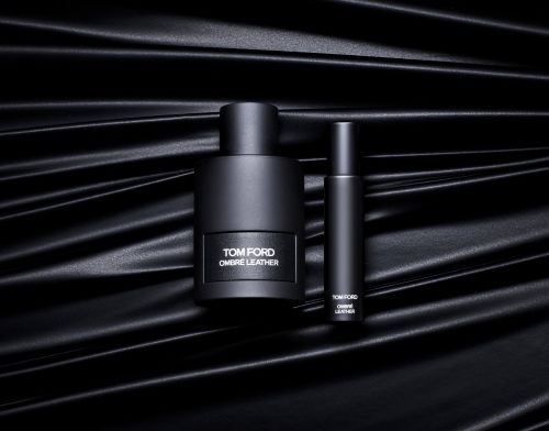 Two Tom Ford Ombre Leather perfume bottles, different sizes, side by side on rippled black surface. Elegant, minimalist, product shot.
