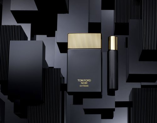 Luxury product shot featuring two sleek, black perfume bottles with gold accents against a backdrop of geometric black blocks.