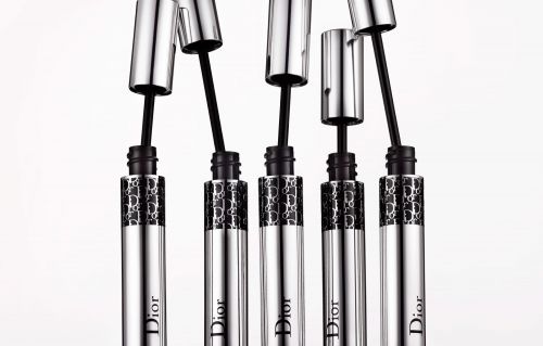 Five Dior mascara tubes with silver caps and black applicators on a white background, showcasing elegant and high-end beauty products.