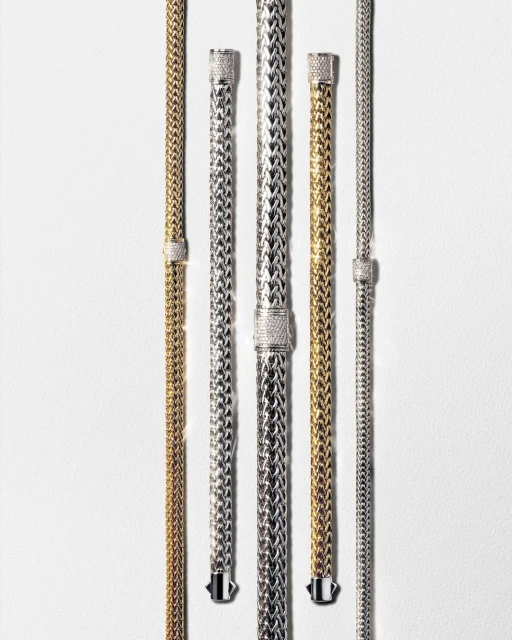 Elevated view of multiple gold and silver woven chain-link bracelets on white background. Jewelry fashion and accessories shot in studio.