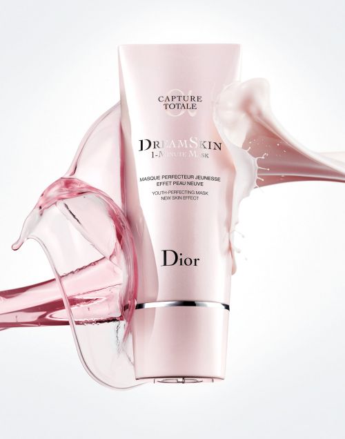 Dior DreamSkin 1-Minute Mask product shot featuring a pink and silver tube surrounded by splashing liquid against a white background.