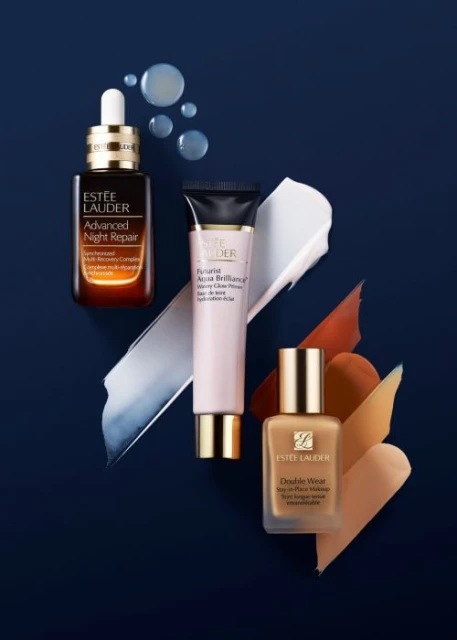 Three Estee Lauder skincare products arranged on a dark blue background with cosmetic swatches, highlighting the brand's beauty offerings.