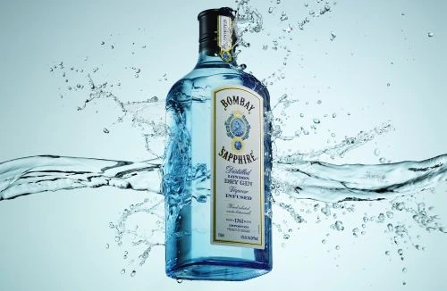 Bombay Sapphire gin bottle in water splash, close-up studio shot for beverage advertising and product promotion, clear glass bottle.