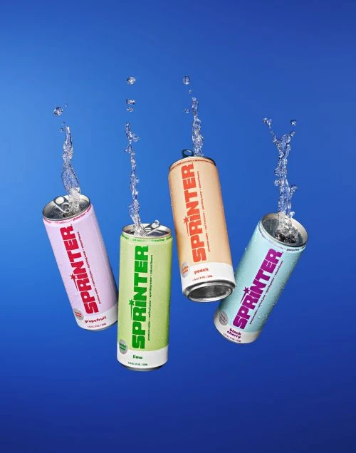 Four cans of Sprinter sparkling water in peach, lime, grapefruit, and blackberry flavors, with water droplets against a blue background.