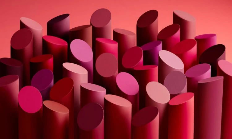 Various shades of red lipstick tubes arranged in an abstract, visually appealing composition against a red background. 