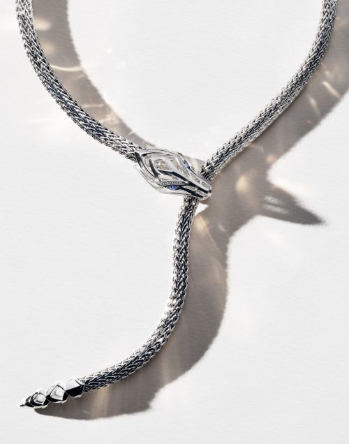 Elegant silver snake necklace with intricate details, styled on a clean white backdrop, showcasing luxury jewelry design.