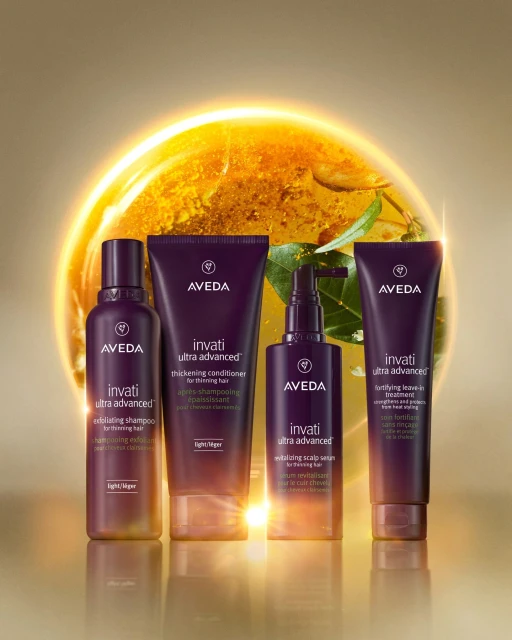 Four Aveda Invati Ultra Advanced hair care products displayed against a warm yellow background with bright, glowing accents.