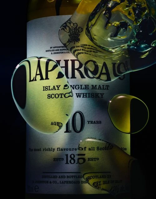 Close-up shot of Laphroaig Islay Single Malt Scotch Whisky bottle, emphasizing the label and its textured surface, with water droplets adding depth.