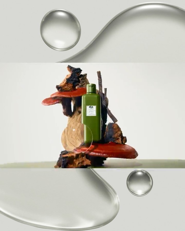 Green skincare bottle sits on a wood sculpture, set against a bright background with clear water droplet-like orbs in the composition.