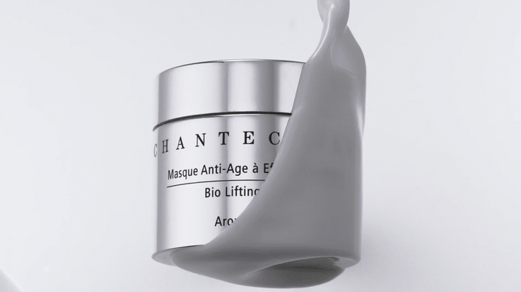 Chantecaille anti-aging cream in silver container with grey cosmetic cream pouring over it against a white backdrop.