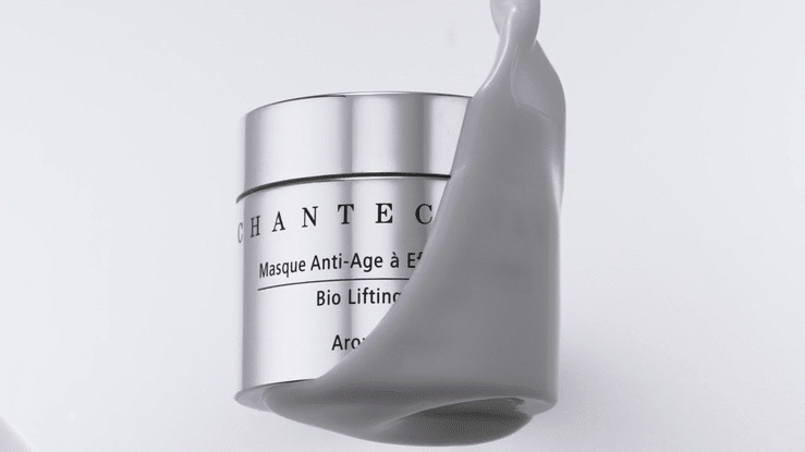 Chantecaille anti-aging cream in silver container with grey cosmetic cream pouring over it against a white backdrop.