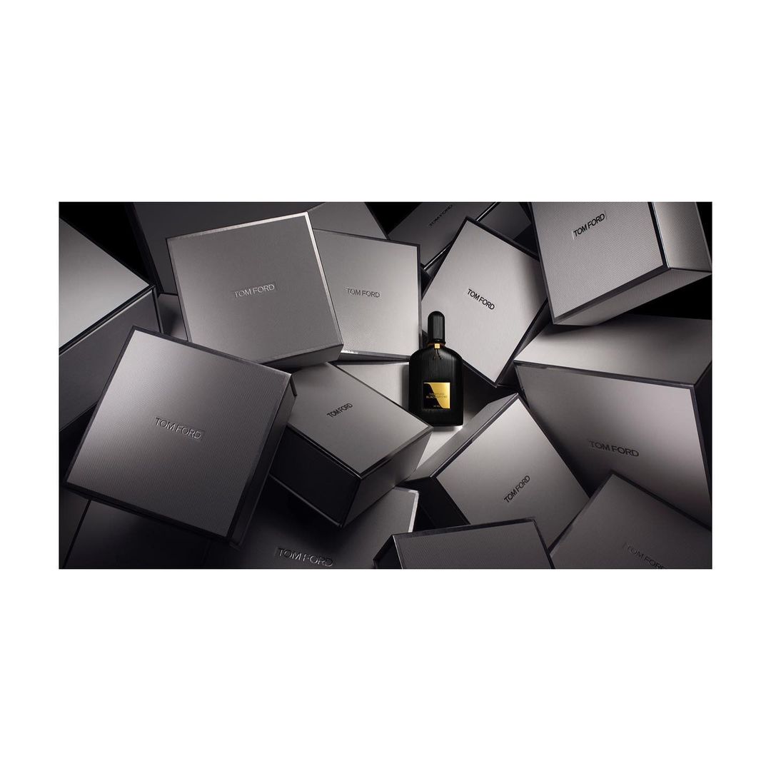 Tom Ford Black Orchid perfume bottle on a pile of Tom Ford gift boxes, in a studio, product shot for beauty and fashion.