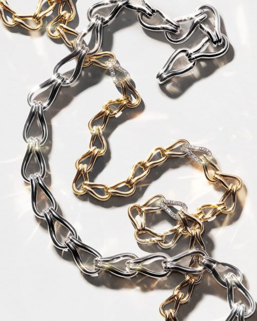 A close-up shot of a gold and silver chain necklace, showcasing the interlocking links and elegant design on a bright, clean surface.