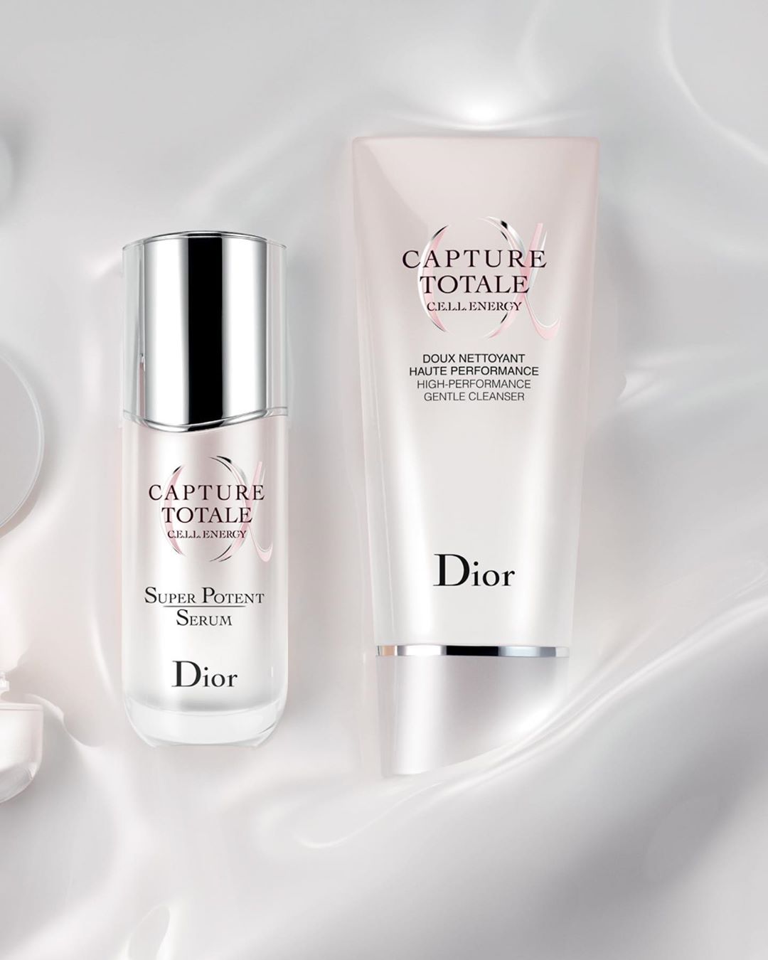 Dior Capture Totale skincare set featuring serum and cleanser against a white silky background. Cosmetic product photography.